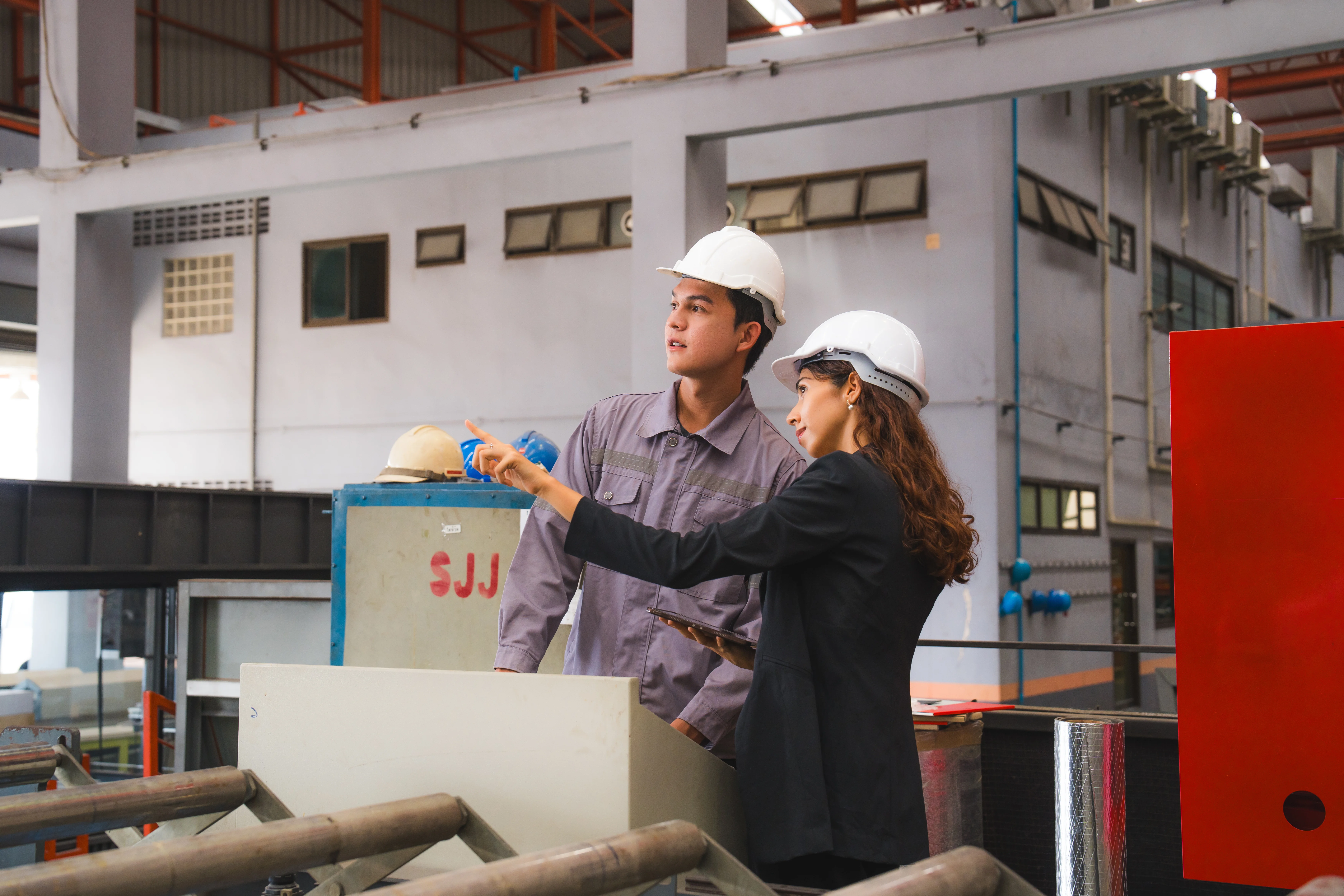 Eine technische Leiterin oder Inspektorin und ein Mechaniker oder Techniker prüfen die Qualität einer Blechbearbeitungsmaschine in der Industrie, in der Fertigung oder in einer Fabrik.