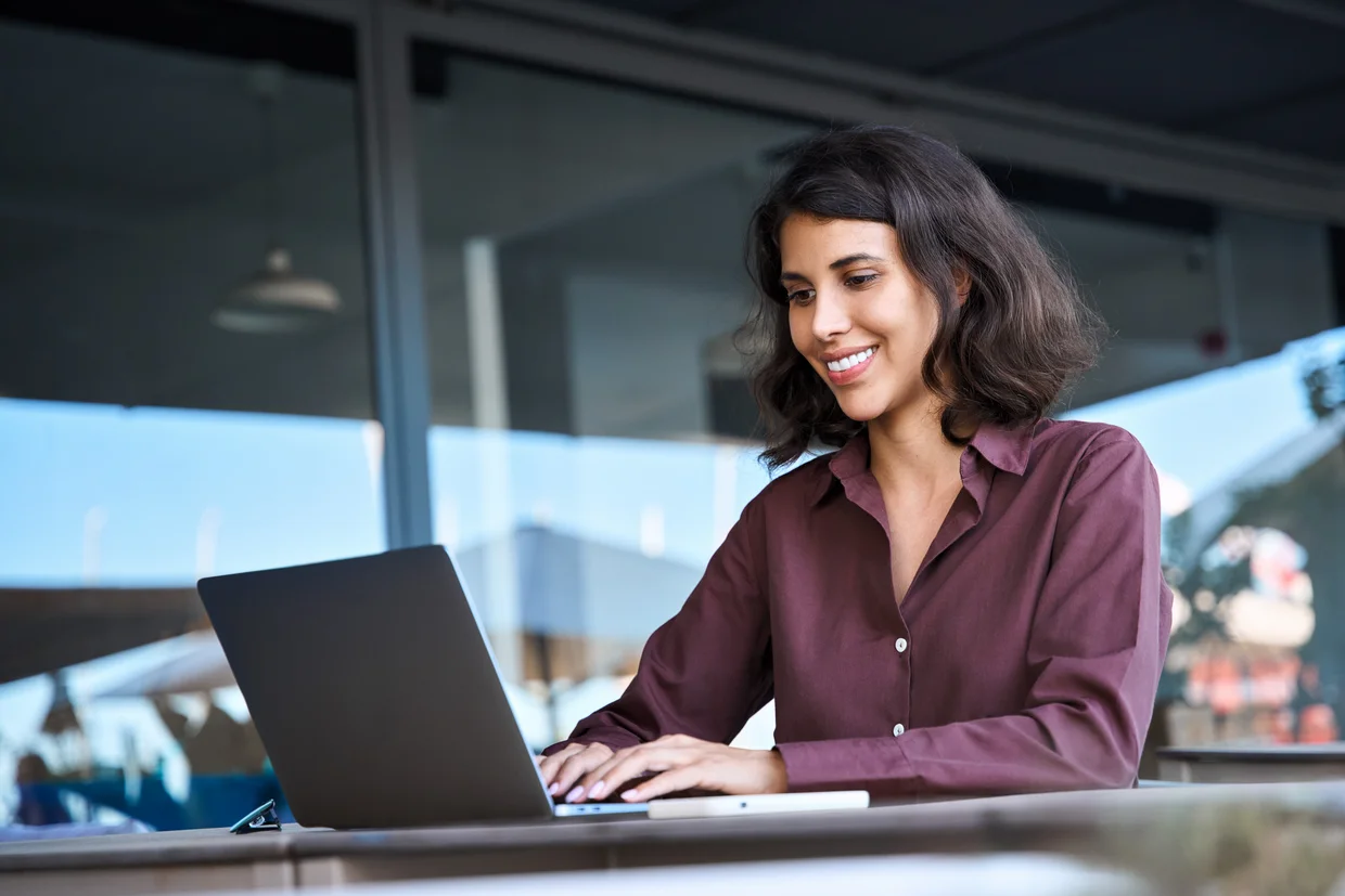 tudentin, die einen Laptop zum Studieren benutzt und im Freien im Bürogebäude sitzt.