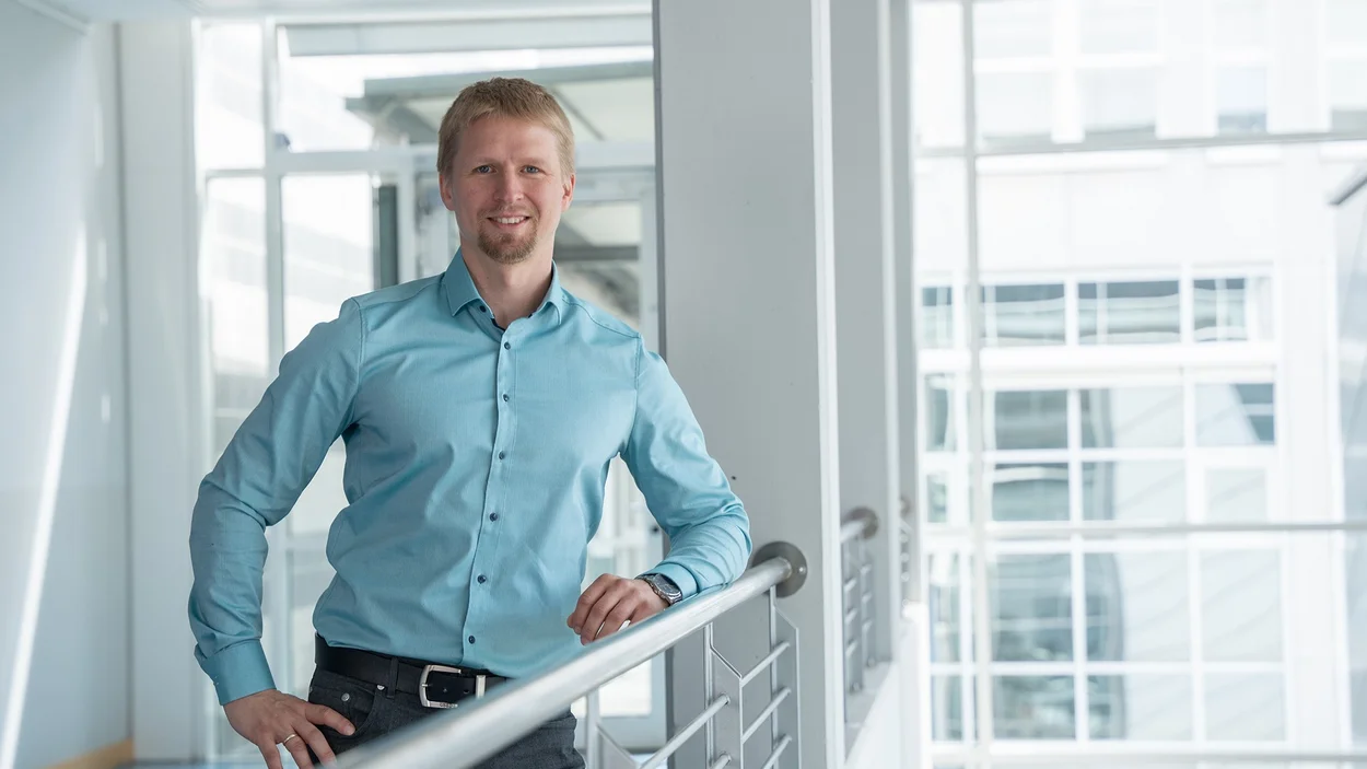 Professor Wasser Professor Florian Wasser steht in blauem Hemd am Geländer