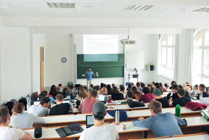 250605-thb-schnuppervorlesung.jpg Das Bild zeigt Studierende in einem Hörsaal der Technischen Hochschule Bingen und einen Lehrenden vor einer großen Tafel, der gerade etwas erklärt.